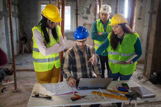 istock Team of workers at construction site discussing about the project 1398144237