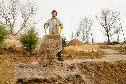 Photo of a young man building a footpath in his backyard.