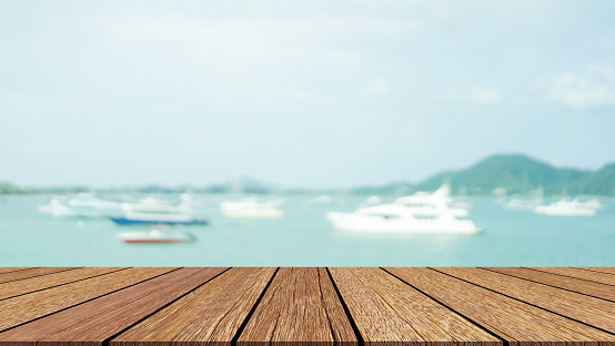 blurred yacht and sailboat  on the ocean with blue natural sky summer with old  wood  background texture tabletop for advertise,show,promote product on display