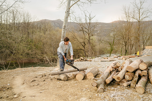 Photo of a young man chopping firewood by himself for a winter season