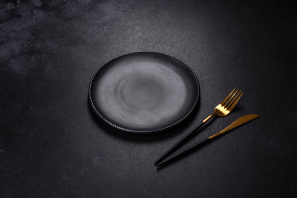istock Black plate on a black background. Flat lay, top view, copy space 1398146561