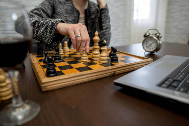 photo rapprochée d’une femme d’affaires jouant aux échecs en ligne à la maison pendant la quarantaine - chess board room business strategy photos et images de collection