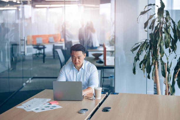 istock Attentive asian businessman working on laptop at workplace in modern office 1398149397