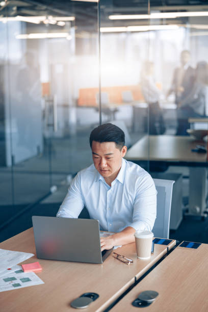 istock Focused asian businessman working on laptop at her workplace in modern office 1398149406