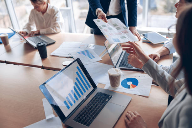 istock Close up of business people consider documents with graphs in a modern office during meeting 1398149457