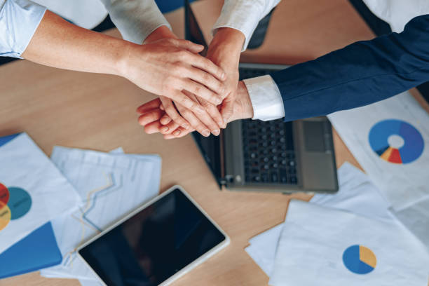 istock Young business people working at office are holding hands together top view close-up teamwork 1398149498