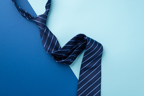 Father's Day concept. Top view photo of blue striped tie on bicolor blue background with empty space