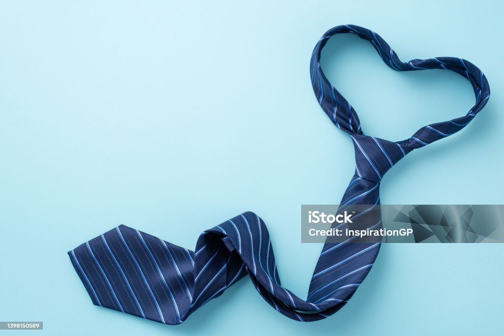 Father's Day concept. Top view photo of heart shaped blue necktie on isolated pastel blue background with copyspace Necktie Stock Photo