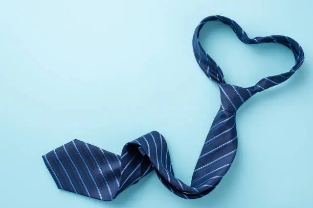 Photo of Father's Day concept. Top view photo of heart shaped blue necktie on isolated pastel blue background with copyspace