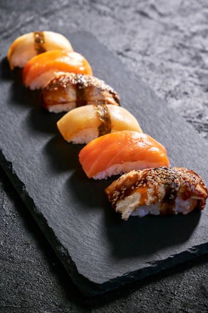 istock Assorted sushi with salmon, eel and escolar on black stone plate on dark background. Minimal concept 1398150662