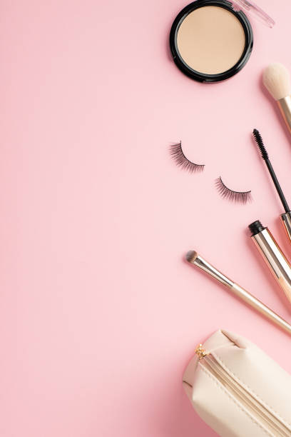 istock Make up beauty concept. Top view vertical photo of compact powder container makeup brushes mascara false eyelashes and cosmetic bag on pastel pink background with empty space 1398150702