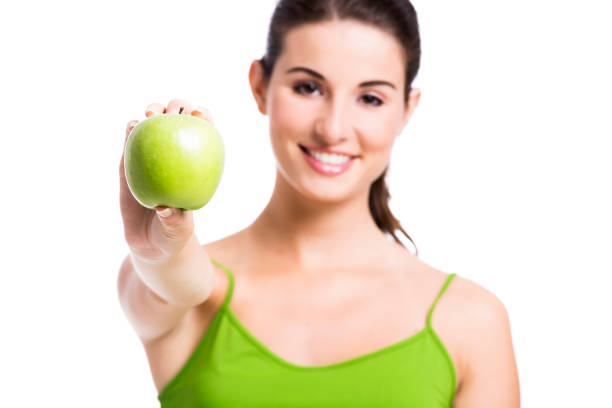 Healthy woman showing a green apple, isolated over a white background