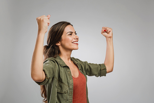 Beautiful and successful young woman with arms raised