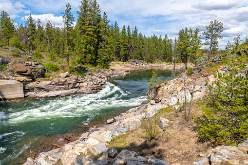 The Spokane River as it runs through the community forest area at Falls Park near the dam and waterfall in the rural city of Post Falls, Idaho, USA.