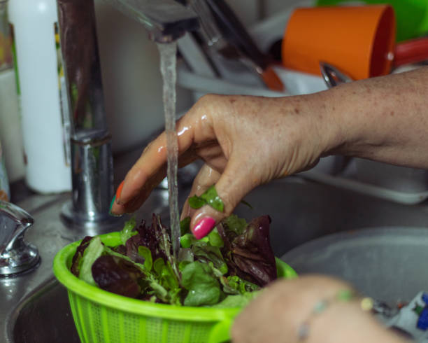 istock Woman with painted nails washing lettuce in the kitchen 1398154866