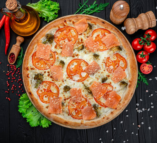 istock Delicious hot pizza with salmon, tomatoes and different spices 1398155829