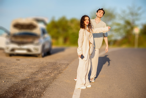 Young couple hitchhiking because their car broke down