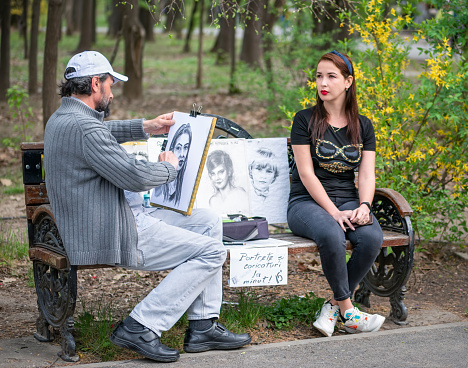 Bucharest, Romania - 03.26.2021: Street artist cartoonist or painter making portraits to people in Herestrau park (Kink MIhai I), Bucharest