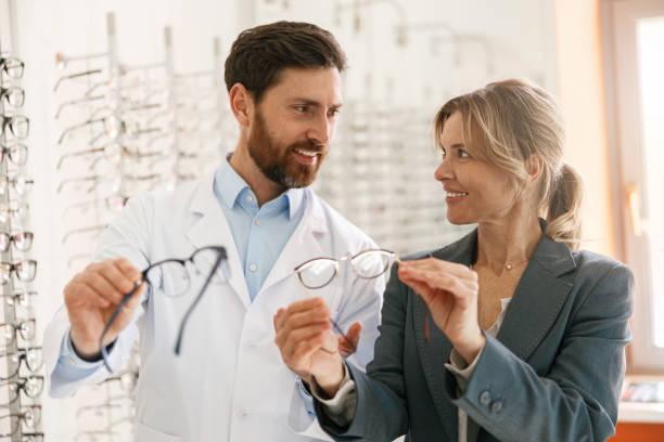 istock Smiling ophthalmologist helping client to choose glasses in optic store 1398162726