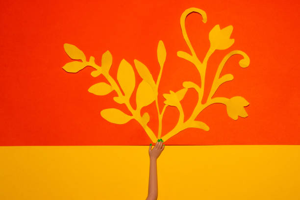 hands from which yellow flowers come out on an orange background, creative art summer design