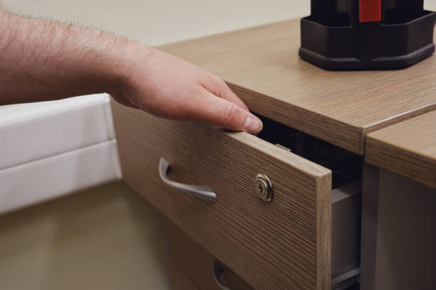 A close-up view of a vintage wooden roll-top desk paired with a worn spindle-back chair, both showcasing decades of use and craftsmanship. The desk features multiple drawers and open pigeonholes for storage, evoking an early 1900s workspace aesthetic. Beside it stands a tall, dark filing cabinet, adding to the scene’s nostalgic, archival ambiance. The warm, natural wood tones and soft lighting enhance the preserved charm of this historical interior.