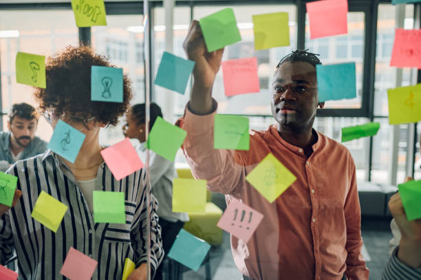 istock Multiracial team at work writing ideas on sticky notes on the glass wall 1398168642