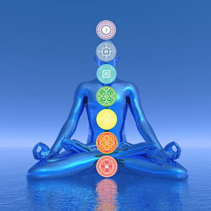 Silhouette of a man meditating with seven colorful chakras upon ocean in blue background - 3D render