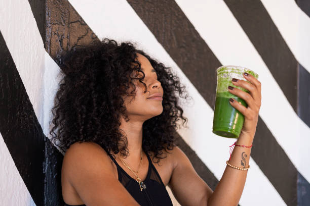 istock afro woman is seated drinking her green juice 1398174741