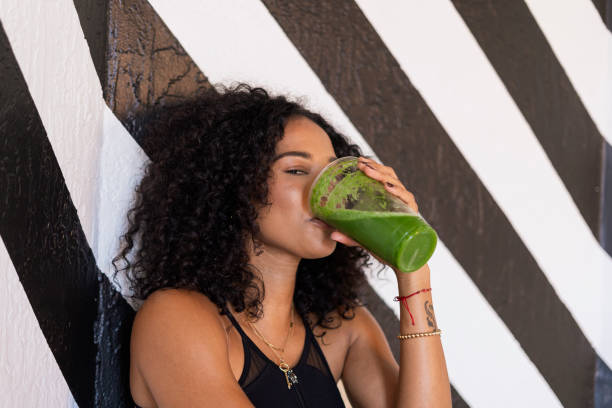 istock afro woman is seated drinking her green juice 1398174882