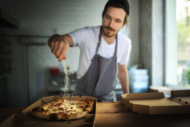 chef de pizza que sirve pizza recién horneada en una caja de entrega. - commercial kitchen bakery front view baking fotografías e imágenes de stock