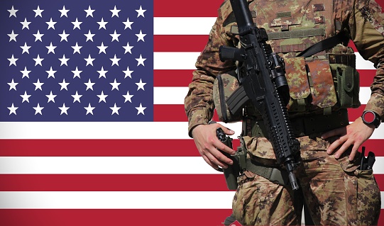 Army man standing in front of american flag with rifle