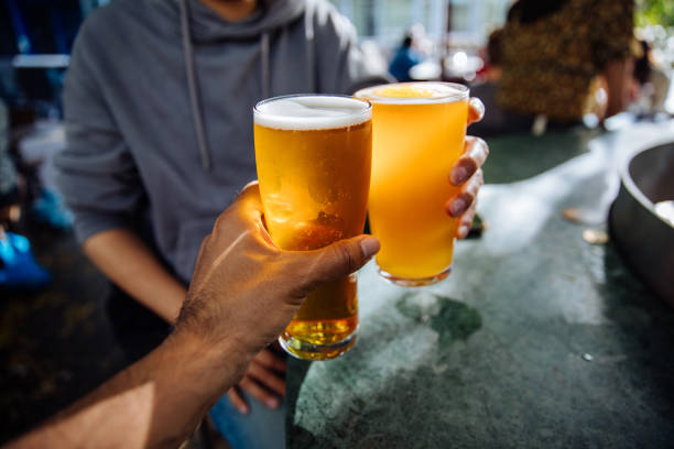 close up of a couple toasting with beer in a pub - beer pub women pint glass imagens e fotografias de stock