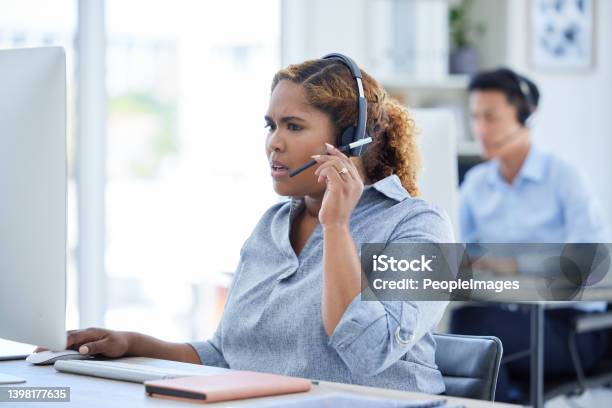 One Stressed And Confused Mixed Race Call Centre Telemarketing Agent Talking On A Headset While Working On A Computer In An Office Young Shocked African American Female Consultant Dealing With Panic Crisis And Difficult Caller For Customer Support Stock Photo - Download Image Now