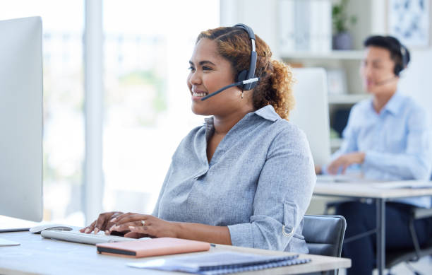 istock One happy young mixed race female call centre telemarketing agent talking on a headset while working on a computer in an office. Confident and friendly african american businesswoman consultant operating a helpdesk for customer service and sales support 1398177636