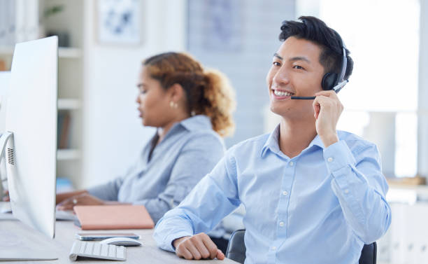 istock One happy young asian male call centre telemarketing agent talking on a headset while working on a computer in an office. Confident and friendly businessman consultant operating a helpdesk for customer service and sales support 1398177651
