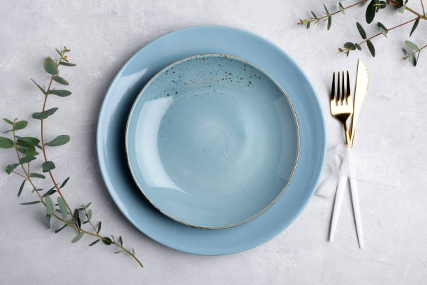istock Festive table setting with blue ceramic plate, golden cutlery set and fresh eucalyptus leaves on grey table plate mockup 1398177660