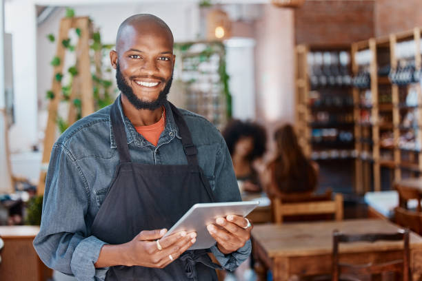 istock Young african american businessman working in a retail store using a digital tablet device. Portrait of a smiling small business owner, entrepreneur buying stock online using wireless technology 1398179490
