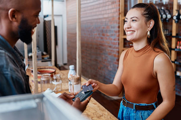 istock Happy hispanic customer paying for a meal in a restaurant using a nfc machine and credit card. Smiling young woman making a purchase in a store with her debit card and a pos machine. Woman paying bill 1398179589