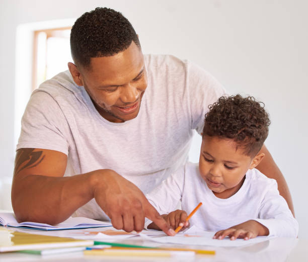 istock Mixed race boy learning and studying in homeschool with dad. Man helping his son with homework and assignments at home. Parent teaching child to colour and write at home during lockdown 1398180285