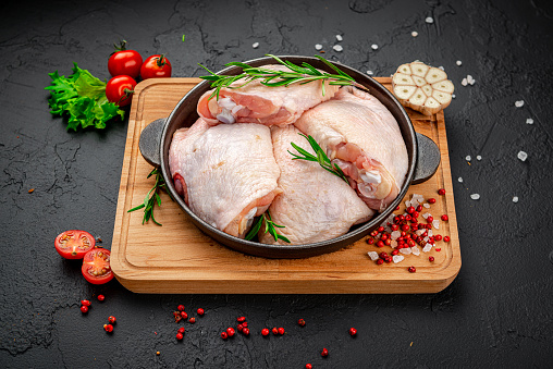 Raw chicken thigh on black background. Healthy food concept.