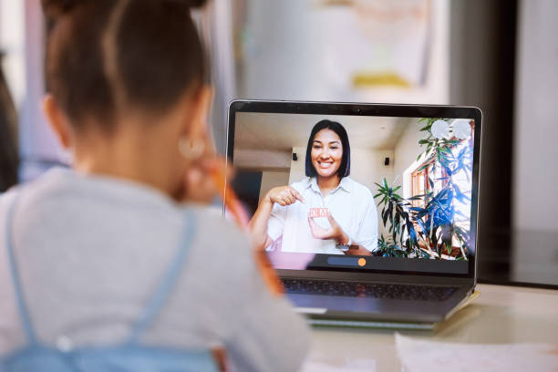 little girl on a video call with her teacher using a laptop. young female teacher doing a virtual lesson using blocks with her student. little girl doing a virtual speech therapy session with a woman - child computer laptop little girls imagens e fotografias de stock