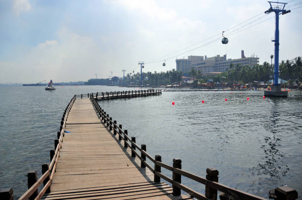 Jakarta, Java, Indonesia: Jakarta Bay (Java sea) corniche - Ancol Bay City - wooden boardwalk and view of the beach and waterfront, with the Ancol gondola cable car and the Mercure hotel Ancol. Ancol Park.
