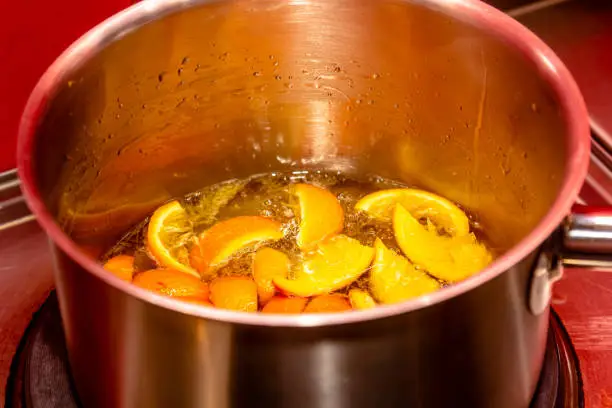 Photo of insisting of tangerine jam (varenye) in sugar syrup in stewpot on hob at home kitchen