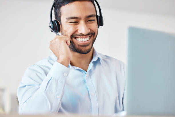 istock Smiling mixed race male call centre agent smiling while wearing a wireless headset. Young man working as a customer service representative and consulting clients online while using a laptop 1398183569