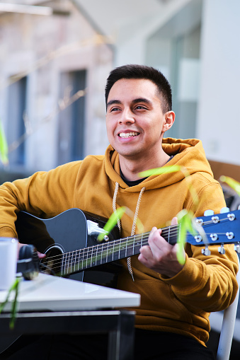 Vertical image of a young man happy and proud to be able to play his guitar as a hobby.