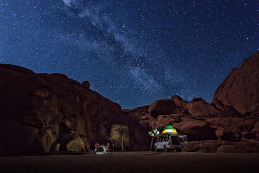 Sleeping in car roof tent outside at Spitzkoppe. Typical camping in Namibia, Africa: on the roof of the offroad vehicle are two tents for four persons. Under a fantastic starry sky with the milky way.