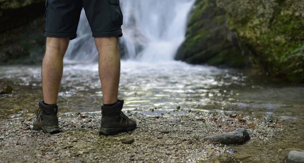 istock man in hiking boots standing by a waterfall 1398189823