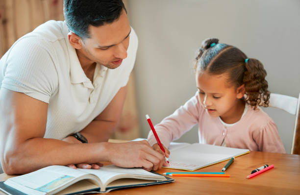 istock Father helping his daughter with her homework. Dad teaching daughter to read and write during homeschool class. Little girl sitting at home with tutor 1398193327