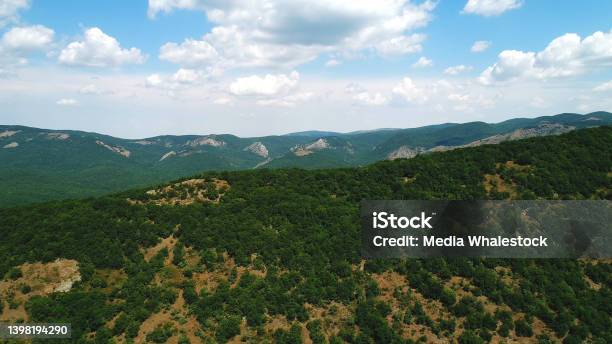 Amazing Endless Landscape Of The High Mountain Ranges Covered By Green Trees And Shrubs Against The Blue Cloudy Sky In Summer Day Shot Beautiful Mountain Scenery Stock Photo - Download Image Now