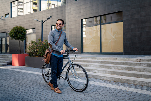 Fast vehicle. Smart handsome man riding a bike in the city while going to work in the office